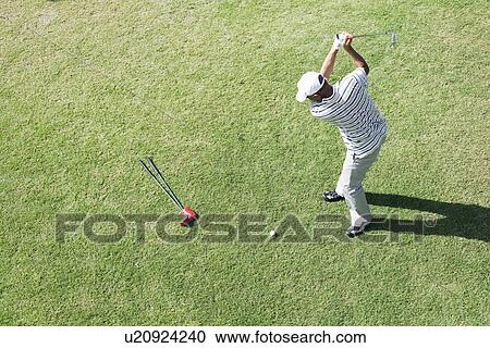 Stock Image - Elevated view of a man hitting golf ball. Fotosearch