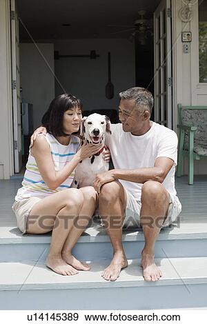 Stock Photo - Husband and wife sitting with dog on steps. Fotosearch