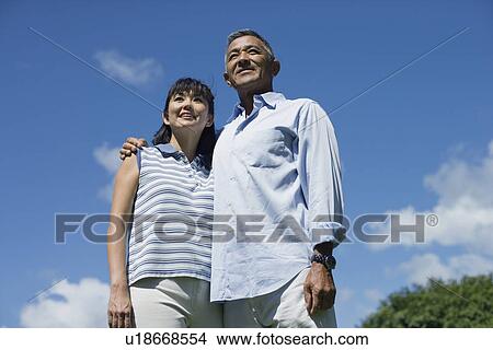 Low angle view of a couple standing together View Large Photo Image Picture - Low angle view of a couple standing together. Fotosearch