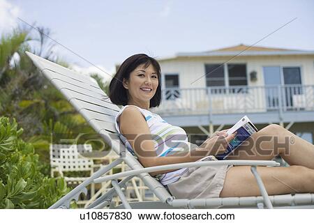 Mid adult woman sitting on deckchair smiling View Large Photo Image Stock Image - Mid adult woman sitting on deckchair smiling. Fotosearch
