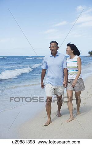 View of a couple walking at beach View Large Photo Image Stock Photo - View of a couple walking at beach. Fotosearch