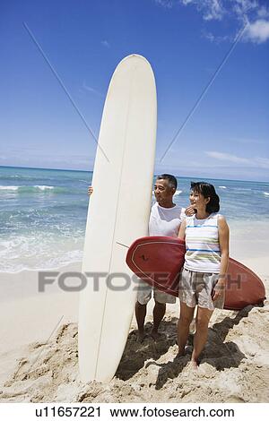 View of a couple with surfboards at beach View Large Photo Image Stock Image - View of a couple with surfboards at beach. Fotosearch