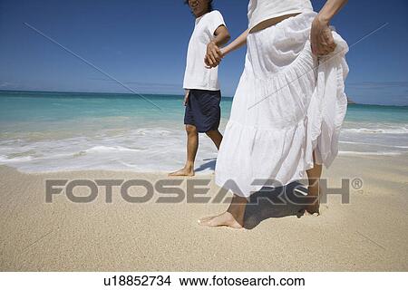 A couple holding hands and walking on beach View Large Photo Image Picture - A couple holding hands and walking on beach. Fotosearch