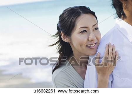 Stock Image - A young couple standing at beach. Fotosearch