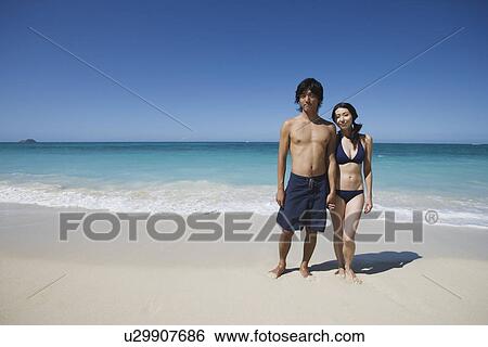 A young couple standing at beach View Large Photo Image Stock Photograph - A young couple standing at beach. Fotosearch