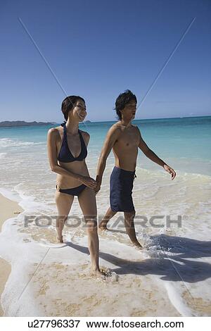 Stock Photo - A young couple walking on beach. Fotosearch