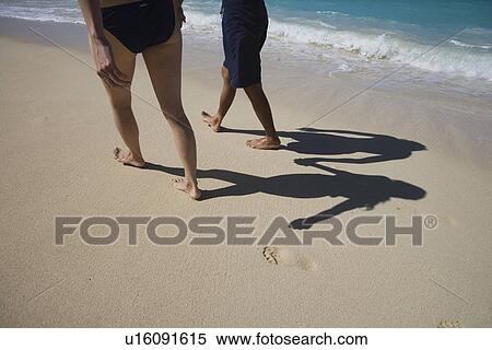 Low section of a couple walking on beach View Large Photo Image Stock Photography - Low section of a couple walking on beach. Fotosearch