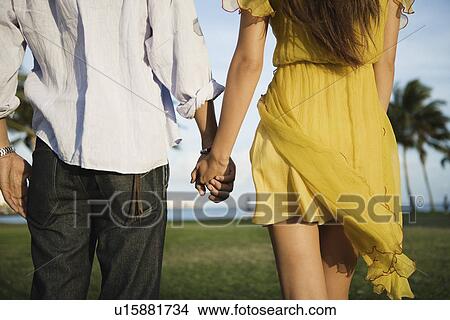 Midsection of a couple holding hands View Large Photo Image Picture - Midsection of a couple holding hands. Fotosearch