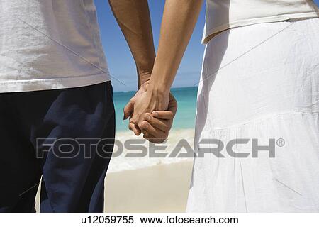 Stock Photography - Midsection of a couple holding hands. Fotosearch