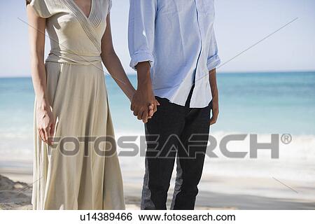 Midsection of a couple standing at beach View Large Photo Image Stock Photograph - Midsection of a couple standing at beach. Fotosearch