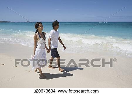 Profile of a young couple walking on beach View Large Photo Image Picture - Profile of a young couple walking on beach. Fotosearch