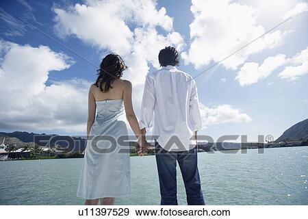 Rear view of a young couple holding hands View Large Photo Image Stock Photo - Rear view of a young couple holding hands. Fotosearch