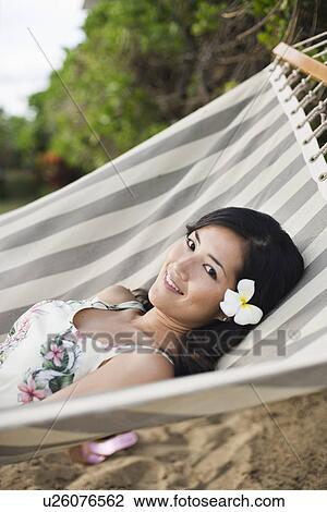 Stock Image - A woman lying on hammock at beach. Fotosearch