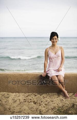 A woman sitting on wall at beach View Large Photo Image Stock Photo - A woman sitting on wall at beach. Fotosearch