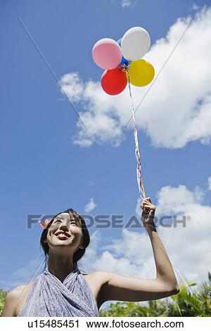 Stock Image - A young woman holding balloons. Fotosearch