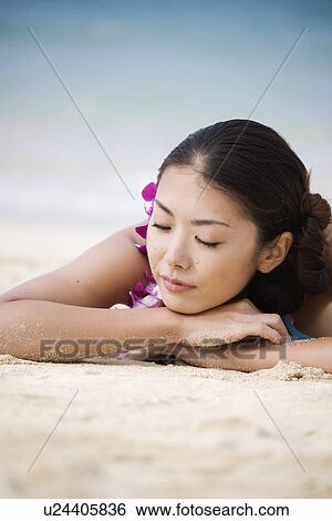 A young woman lying on sand at beach View Large Photo Image Stock Photograph - A young woman lying on sand at beach. Fotosearch