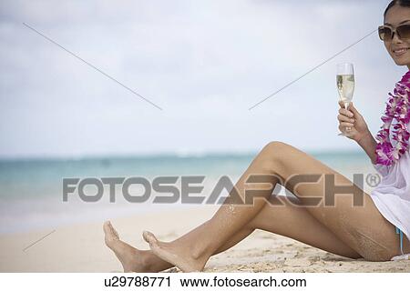 A young woman sitting with wineglass at beach View Large Photo Image Stock Image - A young woman sitting with wineglass at beach. Fotosearch