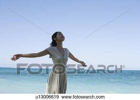 A young woman with arms outstretching on beach View Large Photo Image Stock Photo - A young woman with arms outstretching on beach. Fotosearch