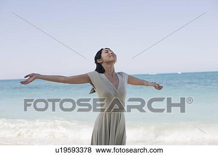 A young woman with arms outstretching at beach View Large Photo Image Stock Photo - A young woman with arms outstretching at beach. Fotosearch