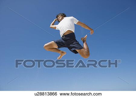 Low angle view of a young man jumping View Large Photo Image Stock Photograph - Low angle view of a young man jumping. Fotosearch