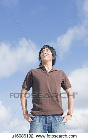 Stock Image - Low angle view of a young man looking up. Fotosearch