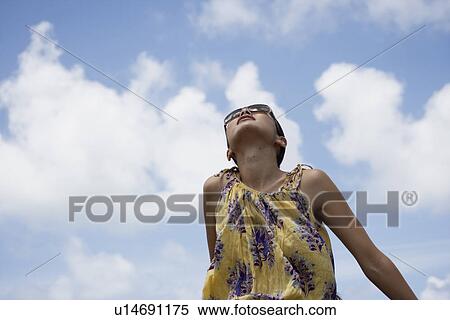 Stock Photography - Low angle view of a young woman looking upward. Fotosearch