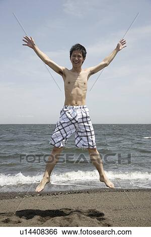 Portrait of a young man jumping on beach View Large Photo Image Stock Photograph - Portrait of a young man jumping on beach. Fotosearch