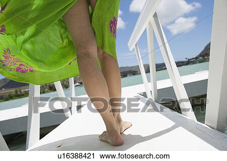 Stock Image - Rear view of a woman walking on a pier. Fotosearch