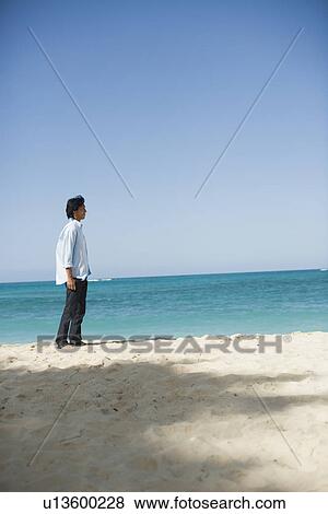View of man standing on beach View Large Photo Image Stock Photo - View of man standing on beach. Fotosearch
