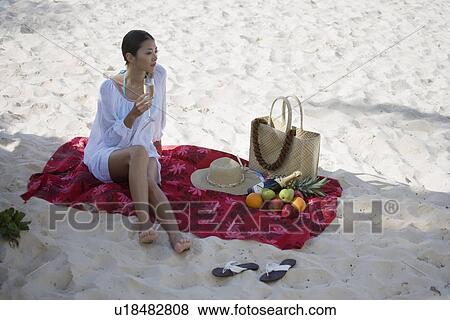 A young woman holding wineglass and sitting at beach View Large Photo Image Stock Photo - A young woman holding wineglass and sitting at beach. Fotosearch
