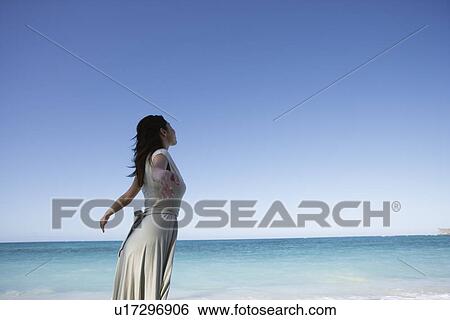 A young woman standing on beach View Large Photo Image Stock Photograph - A young woman standing on beach. Fotosearch