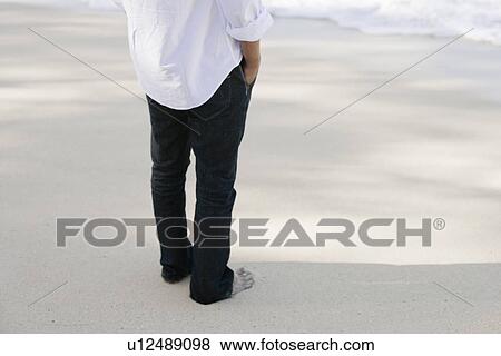 Low section of a man standing at beach View Large Photo Image Stock Photo - Low section of a man standing at beach. Fotosearch