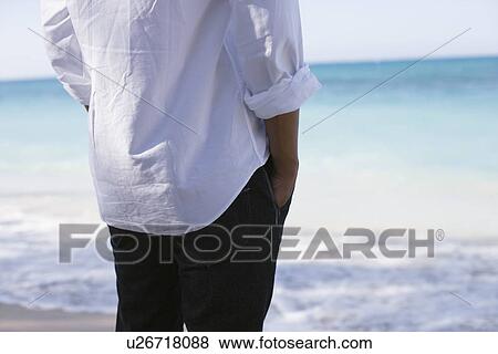Midsection of man standing on beach View Large Photo Image Stock Photo - Midsection of man standing on beach. Fotosearch