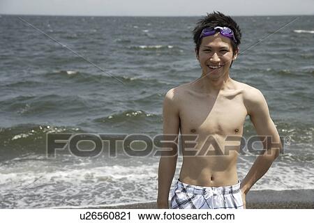 Stock Image - Portrait of a young man smiling on beach. Fotosearch