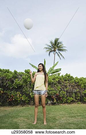 Portrait of a young woman holding balloon View Large Photo Image Stock Photo - Portrait of a young woman holding balloon. Fotosearch