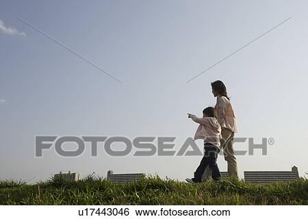 Stock Photograph - Daughter pointing finger as mother walk along. Fotosearch