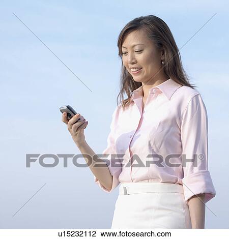 Low angle view of a mid adult woman operating a mobile phone View Large Photo Image Stock Image - Low angle view of a mid adult woman operating a mobile phone. Fotosearch