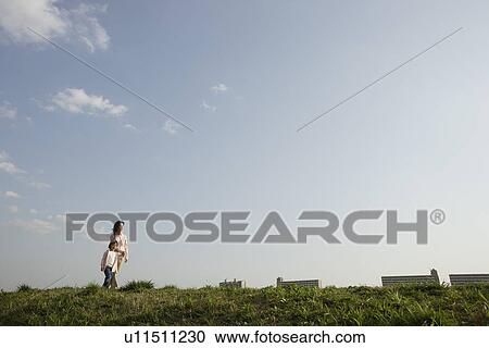 Stock Image - Low angle view of a mother and daughter walking along pathway. Fotosearch