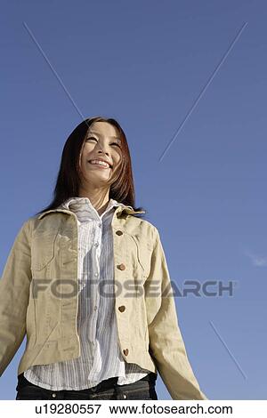 Low angle view of a smiling young woman View Large Photo Image Stock Photo - Low angle view of a smiling young woman. Fotosearch