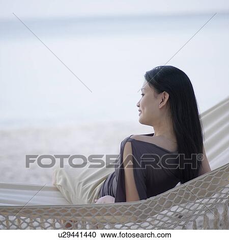 Rear view of a young woman relaxing in a hammock View Large Photo Image Stock Image - Rear view of a young woman relaxing in a hammock. Fotosearch