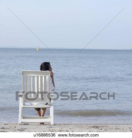 Rear view of a young woman talking on a mobile phone at the beach View Large Photo Image Stock Photograph - Rear view of a young woman talking on a mobile phone at the beach. Fotosearch