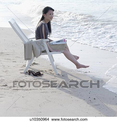 Side profile of a businesswoman sitting on a chair at the beach View Large Photo Image Picture - Side profile of a businesswoman sitting on a chair at the beach. Fotosearch