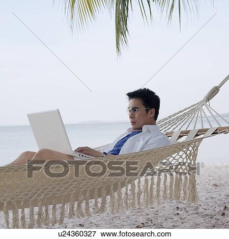 Side profile of a mid adult man lying in a hammock using a laptop View Large Photo Image Stock Photo - Side profile of a mid adult man lying in a hammock using a laptop. Fotosearch