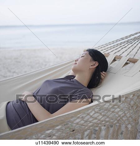 Stock Image - Side profile of a young woman relaxing in a hammock. Fotosearch