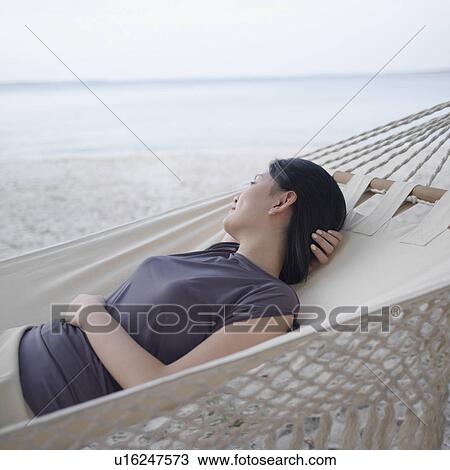 Stock Image - Side profile of a young woman relaxing in a hammock. Fotosearch