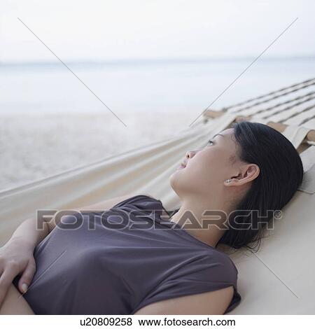 Side profile of a young woman relaxing in a hammock View Large Photo Image Stock Photo - Side profile of a young woman relaxing in a hammock. Fotosearch