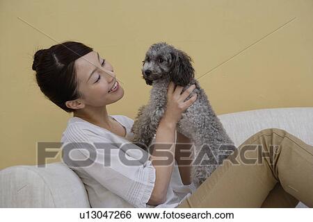 Side view of a young woman holding a dog View Large Photo Image Stock Photograph - Side view of a young woman holding a dog. Fotosearch