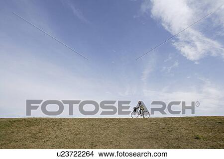 Side view of a young woman riding a bicycle View Large Photo Image Picture - Side view of a young woman riding a bicycle. Fotosearch