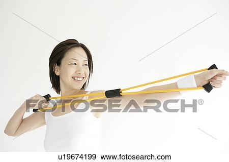 Stock Photo - A young woman smiles as she uses the stretching rope for an exercise. Fotosearch