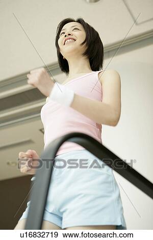 Low angle view of a young woman jogging on a walker as she exercises in a well equipped gym View Large Photo Image Stock Photo - Low angle view of a young woman jogging on a walker as she exercises in a well equipped gym. Fotosearch